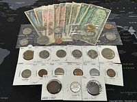 Wide view showing all included Canadian banknotes, coins, and proof-like sets arranged on a black map background.