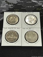Four 1968 Canadian silver dollar coins viewed from reverse side showing island design variants: Normal Island, Small Island, Normal Island Extra Water Line, No Island.