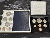 Two sets of Canadian coins in specimen condition: one in white plastic holder with multiple coins, the other in a black velvet-lined case with white cover showing Royal Canadian Mint label.