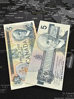 Two Canadian five dollar banknotes, one from 1979 and one from 1986, laid flat showing front sides with portraits and denomination.