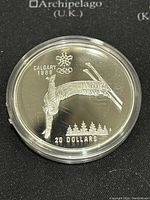 Obverse side showing skier performing freestyle skiing trick with Calgary 1988 Olympic logo and $20 denomination.