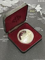 Coin displayed in an open hinged case with red velvet lining, showing the coin depth and details.