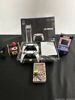 Full view of the four video gaming systems showing the modern wireless console and controllers, the handheld game, the mini arcade game, and joystick controller.