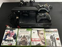 Xbox 360 console, two wireless controllers, power adapter cables, and four game cases
