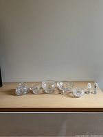 Full view of all crystal tableware items on the shelf: covered butter dish, three bowls, small creamer, and salt and pepper shakers.