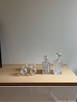 Full set of 2 crystal decanters and 4 snifter glasses displayed on wooden surface against plain background.