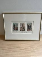 Close-up of framed artwork featuring three small vertical screenprint panels depicting Montreal in snow.