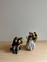 Front view of male and female Royal Doulton balloon seller figurines showing details and colors