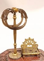 Photo showing the front view of the brass Victorian style toilet roll holder with ornate curved handles and the vintage brass towel bar stand with a decorative base.