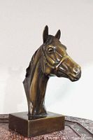 Front angle view of bronze horse head bust sculpture showing detailed face and bridle, mounted on rectangular base.