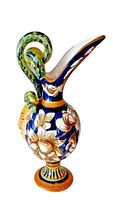 Side front angle of vintage Italian Majolica wine ewer showing hand-painted floral design, curved spout, and green serpentine handle.