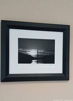 Framed photo showing entire item hanging on wall, featuring dark wood frame and white matting with Washington Monument silhouette at sunset.
