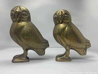 Pair of brass owl sculptures shown side by side, highlighting detailed feather engraving and face features.