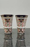 Pair of hexagonal vases standing upright showing front decorative designs.