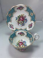 Teacup placed inside matching saucer showing floral design and blue-gold trim