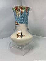 Ivory-colored vase with flared mouth, bulbous base, speckled blue background and red and green painted foliage at lip.