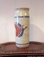 Full view of tall, cylindrical salt-glazed pottery vase with painted flying geese design and blue band accents.