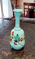 Front view of the turquoise opaline glass vase showing colorful hand painted floral design