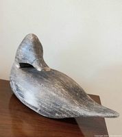 View of carved wooden duck decoy showing whole body and tail with weathered finish and visible wood grain.