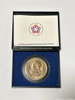 Photo of the 1972 American Revolution Bicentennial Commemorative Medal in its original case accompanied by the informational paper.