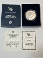 Top-down view of the original presentation box with the coin inside and Certificate of Authenticity and informational papers laid out beneath.
