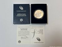 Full view of the presentation box containing the silver coin in its protective capsule alongside the certificate of authenticity.