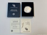 Box showing the coin in protective case, black mint box, and certificate of authenticity opened beneath