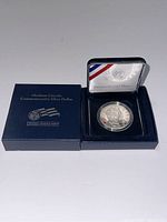 Presentation box with outer sleeve and protective capsule containing the commemorative coin.