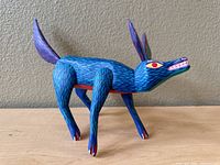 Side view of the blue painted wood coyote or wolflike carving showing the full body and head profile.