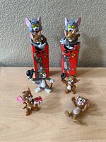 Front view showing all seven Tom and Jerry plastic figures arranged on a surface including two red boxes with Tom and Jerry graphics.