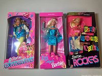 Front view of three boxed Barbie dolls: Barbie Sensations, City Style Barbie, and Barbie and Rockers, all from the 1980s.