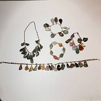 Photo showing all four items in the grouping: two necklaces and two bracelets with stone pendants attached to gold-tone chains.