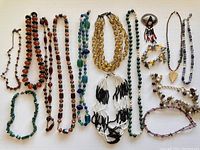 Full view of all necklaces and accessories laid flat on a white surface showing style, color, and size variation