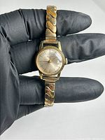 Full view of the vintage Jean Perret wristwatch showing the gold-tone case and curved link bracelet held in a gloved hand.