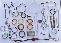 Overview of assorted jewelry including necklaces, bracelets and brooches arranged on white background.