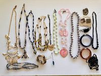 Overview of all necklaces, bracelets, rings, earrings, and pins displayed on flat surface.