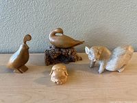 Group photo showing all four wooden animal figurines on a surface against a plain wall.