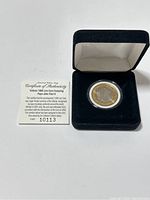 Vatican 1000 Lire coin in black velvet-lined case with Certificate of Authenticity beside it.