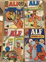 Four ALF comic books arranged on a table showing covers with colorful ALF and other cartoon characters in various scenes.