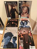 Photo showing all 6 comics stacked upright and leaning against a wall, covers visible including Angel and Buffy themes.