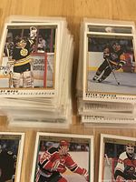 Stack of hockey cards in clear protective sleeves featuring various players including a goalie in Bruins uniform and players from Penguins and Flyers.