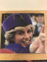 Front cover of the large hardcover book featuring a close-up image of Princess Diana wearing a purple hat, smiling and reaching out.