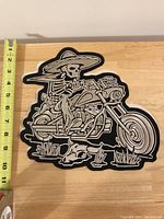 Large embroidered biker patch showing a skeleton in a sombrero riding a motorcycle, measuring about 10 inches tall as shown against a tape measure