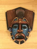 Full face mask showing wood and mixed materials with natural rope accents and textured painted blue face.