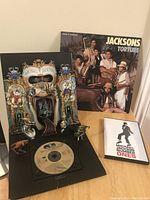 Photo showing Michael Jackson Dangerous Special Collectors Pop-Up CD with intricate 3D artwork and the Jacksons Torture vinyl record album cover behind, alongside the Michael Jackson Number Ones DVD case.