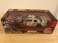 Front angled view of the car in clear window box showing John Wayne and NASCAR branding and number 40 on roof.