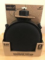 Front view of BLKSMITH Woodsman Canteen in black insulated fabric cover with wooden handle in original packaging.