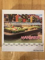 Top view of puzzle box showing image of food display including vegetables, flowers and jars with Mandarin logo and 500 piece puzzle label.