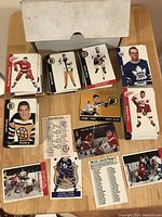 Wide shot of multiple stacks of Parkhurst hockey cards and informational sheets spread on a table with box behind.