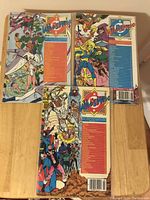 Three Who's Who comic books placed on a wooden table, all in protective bags with visible colorful back covers.